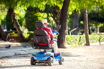 Senior man using electric wheelchair in the park. Lifestyle and independence of disabled people