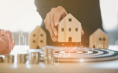 Man hand hold mini wood house model from model on wood table and Targeting the new business...