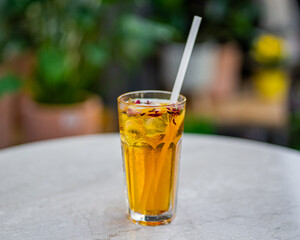 cup of fresh ice tea on table with nature flowers background