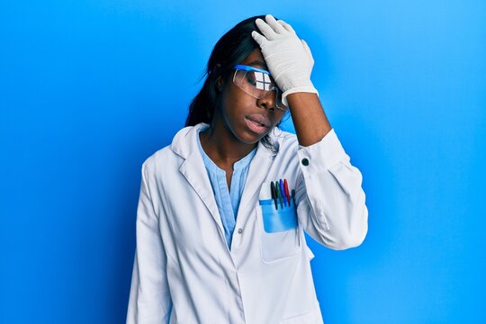 Young african american woman wearing scientist uniform surprised with hand on head for mistake, remember error. forgot, bad memory concept.