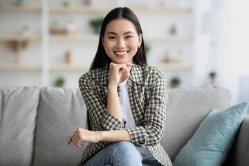 Potrait of happy asian woman sitting on sofa at home