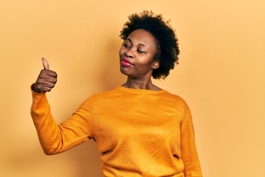 Young african american woman wearing casual clothes looking proud, smiling doing thumbs up gesture to the side
