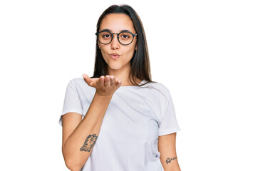 Young hispanic woman wearing casual white t shirt looking at the camera blowing a kiss with hand on air being lovely and sexy. love expression.