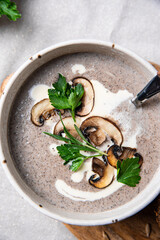 Traditional French mushroom cream soup with sour cream and parsley and rye bun on wooden board on natural linen background .