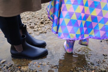 6月の梅雨時の水たまりに入る子どもとママの長靴
