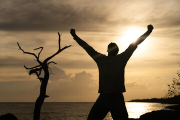 Fototapeta premium Happy exited Man Jumping on sea and Beautiful Sunrise background. Happiness, joy and success concept