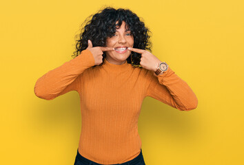 Young hispanic woman wearing casual clothes smiling cheerful showing and pointing with fingers teeth and mouth. dental health concept.