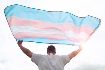 Transgender man holding waving transgender flag, concept picture about human rights, equality in the World - obrazy, fototapety, plakaty
