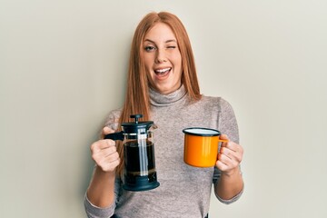 Young irish woman drinking italian coffee winking looking at the camera with sexy expression,...