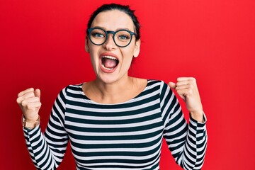 Young caucasian woman wearing casual clothes and glasses celebrating surprised and amazed for success with arms raised and open eyes. winner concept.