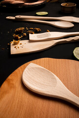 wooden kitchen items, white cloth, seasoning pot, lemons, wood board, black background