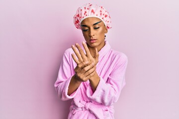 Hispanic man wearing make up wearing shower towel cap and bathrobe suffering pain on hands and...