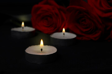 Fototapeta na wymiar Mourning concept. Burning candles and flowers on a black mourning background