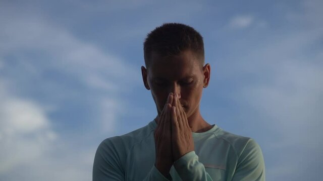 Young Man pray on blue sky background. Repentance, regret and hope concept 