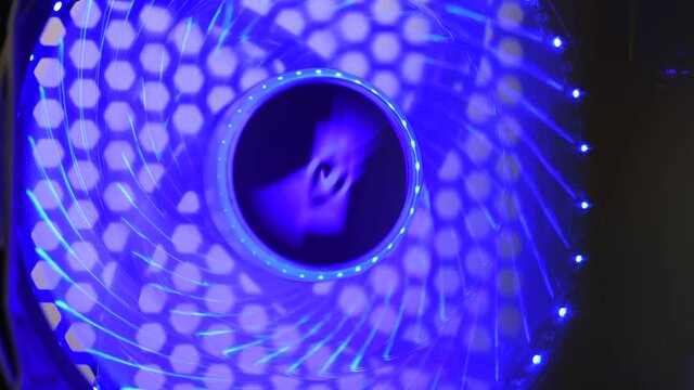 Computer rear fan that rotates and cools. Blue illuminated, with fgb led light. Fan in a desktop case.
