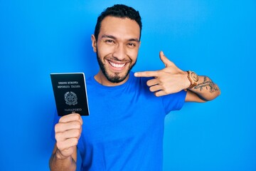Hispanic man with beard holding italy passport smiling cheerful showing and pointing with fingers...