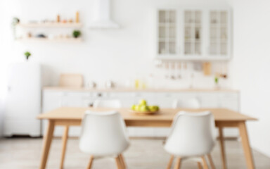 Fototapeta na wymiar Comfortable light kitchen and stylish cozy design. Blurred background with wooden dining table and chairs