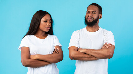 Obraz premium Offended black couple standing with crossed arms, blue studio wall