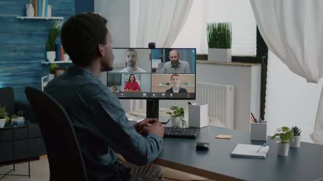 African american man waving to colleagues, talking on online conference internet call using webcam communication. Remote worker working from home keeping distance while using technology