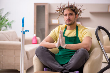 Young male contractor wearing prickly wreath on head cleaning th