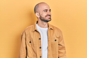 Young bald man wearing casual clothes looking away to side with smile on face, natural expression. laughing confident.