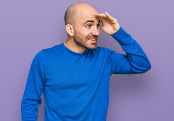 Young hispanic man wearing casual clothes very happy and smiling looking far away with hand over head. searching concept.