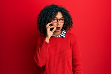 Beautiful african american woman with afro hair wearing sweater and glasses mouth and lips shut as zip with fingers. secret and silent, taboo talking