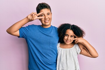 Obraz premium Young hispanic family of brother and sister wearing casual clothes together doing peace symbol with fingers over face, smiling cheerful showing victory