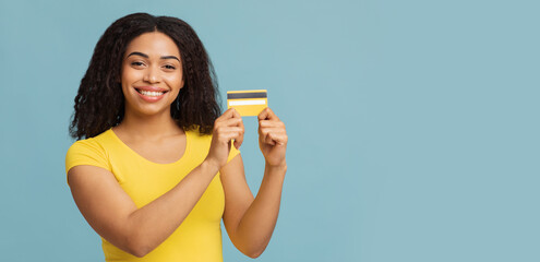 Easy payment concept. Happy african american lady holding credit card, looking and smiling to...