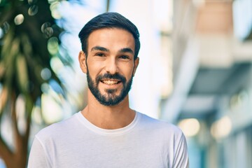 Young hispanic man smiling happy standing at the city.