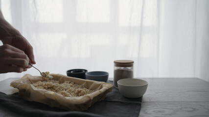 Man making homemade granola with honey and different flakes on oak table