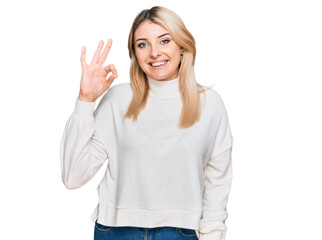 Young caucasian woman wearing casual winter sweater smiling positive doing ok sign with hand and...