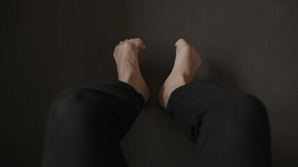 Man sitting on a couch and making feet streych excercise