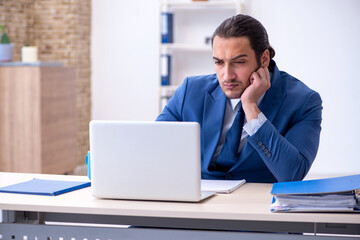 Fototapeta premium Young male employee working at workplace