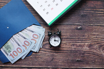 Close up of cash in a envelope , calendar and old clock on table 