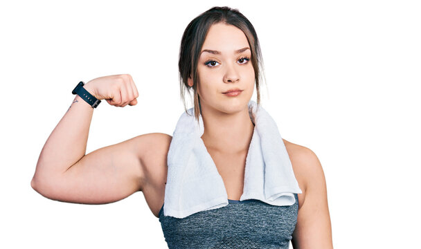 Young hispanic girl wearing sportswear and towel strong person showing arm muscle, confident and proud of power