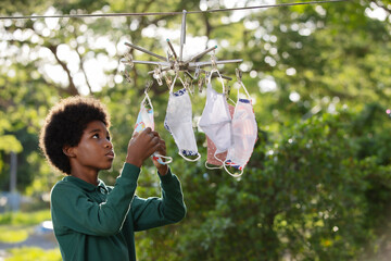 Fototapeta premium Africa children boy hanging the reusable fabric protective face masks at outdoors and drying in a sunny day.