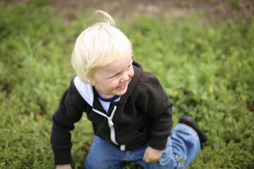 Happy little boy playing on lush green grass