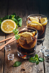 Fresh made Cuba Libre with brown rum, cola, mint and lemon on wooden background