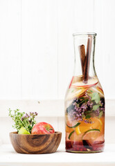 Summer infused detox.cold waters with fresh fruits, berries and cinnamon in glass bottle on white wooden background