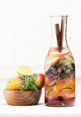 Summer detox.  infused lemonade with fresh fruits, berries and cinnamon in a glass bottle on a white wooden background