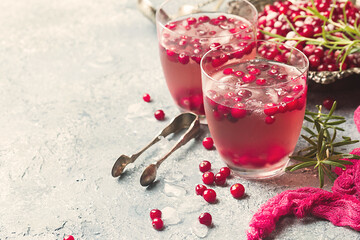 Refreshing drink with cranberries, ice and rosemary on gray stone background. Christmas cocktail