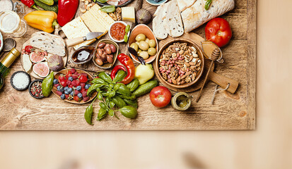 Fototapeta na wymiar Top view table full of food. Italian antipasti wine snacks set. Cheese variety, nuts, Mediterranean olives, sauces, Prosciutto vegatables and berries and wine over wooden background