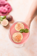 Pink cocktail with fig and basil on light background close up