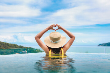Asian travel bikini woman relax in infinity pool resort on phuket beach Thailand