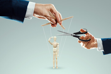 A man's hand cuts the threads between the puppeteer and the puppet with scissors. The concept of liberation from slavery, freedom, shadow government, world conspiracy, manipulation, control.