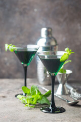Closeup of green cocktails in martini glasses with mint leaves over gray background