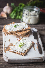 Crispbread toast with homemade herb and garlic cottage cheese on wooden background