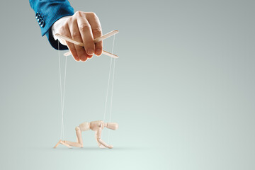 Male hand, puppeteer controls the puppet puppet with strings. A doll on her knees. The concept of...