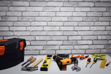 Set of various work tools and toolbox on grey surface near brick wall with copy space.